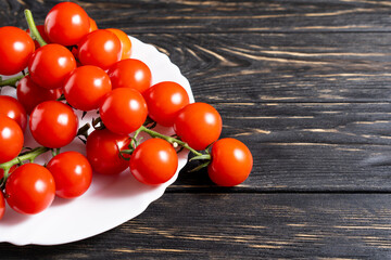 Fototapeta na wymiar Cherry tomatoes in the white plate on the wooden table