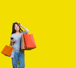 Fototapeta na wymiar Banner of Attractive Asian smiling young woman Carrying a shopping coloful bag, mobile phone and sunglasses on aisolated yellow color background, copy space and studio,black friday season sale concept