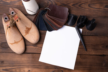 Leather samples for shoes and wooden shoe last on dark wooden table.
