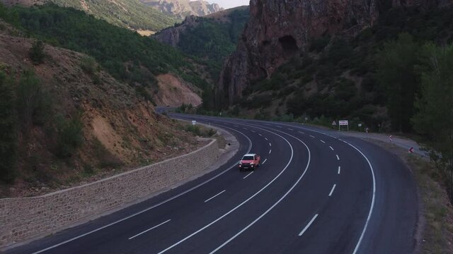 Travel alone one pickup car driving on asphalt winding empty wide serpentine highway through rocky mountains in Turkey. Aerial drone wide view at summer sunset