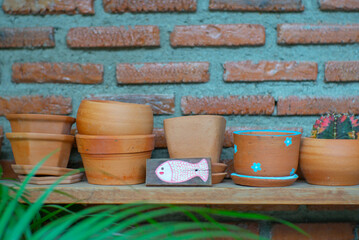 Closeup empty clay pot on the wooden shelf with blurred bricklayer wall background