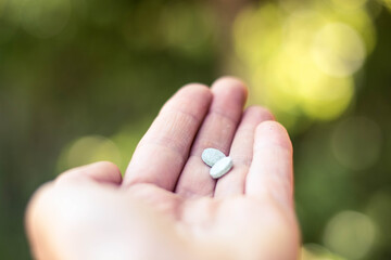 hand with green natural vitamin pills