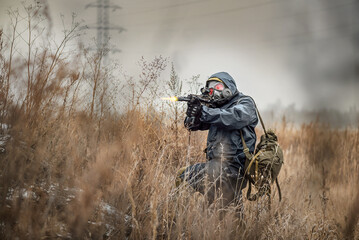 Post apocalypse soldier in a gas mask and rifle is aiming.