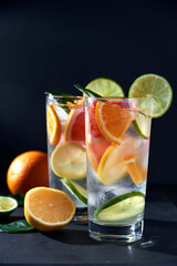 Health care, fitness, healthy nutrition diet concept. Fresh cool homemade citrus infused detox water with grapefruit, orange, lemon and lime and ice in glasses on dark background.