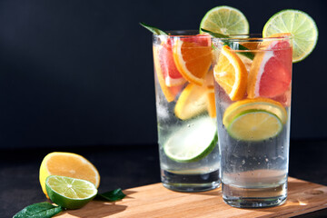 Health care, fitness, healthy nutrition diet concept. Fresh cool homemade citrus infused detox water with grapefruit, orange, lemon and lime and ice in glasses on dark background.