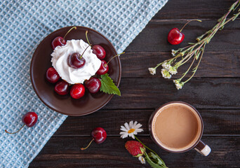 Cake with berries, on a brown saucer, a Cup of coffee on a wooden background, wild flowers. Beautiful Breakfast