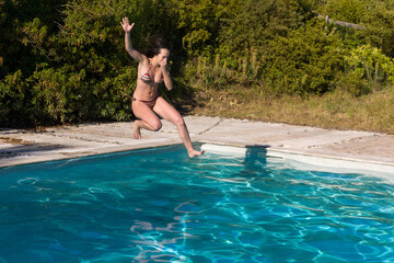 Young woman jumping into the swimming pool almost in the water