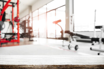 Fototapeta premium Empty wooden desk space and blurry background of fitness gym for product display montage.