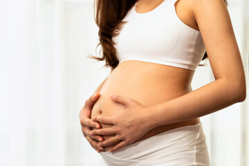 Asian teen beautiful in Pregnancy 20 week posing relex smile in bedroom her by touch cute pregnant belly beside windows
