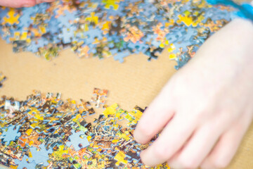 Close-up of female hands assembling a puzzle at home. Concept - quarantine home entertainment