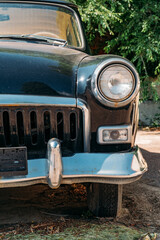 Old abandoned retro car. Detail of the front headlight