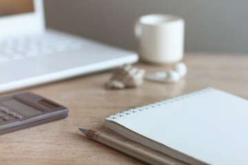 Home office workspace desk with laptop, headphones, pen, diary, blank, notepad, shell, calculator, cup on wooden table background. Flat lay, top view. Minimal workspace, business concept
