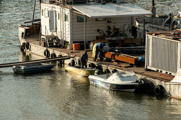 Two sailors work on a large old barge. Builders are loading building material timber onto a boat for transportation. Work of sailors on a schooner