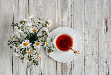 a bouquet of daisies and tea on a white wooden table