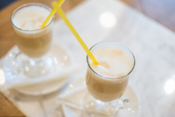 Two latte coffee in the glass with yellow straws