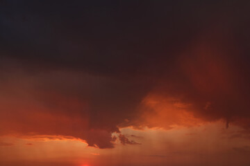 Edge of rain cloud in warm sunset light. Panoramic view of virga and clouds in vivid orange light. Hot summer rainfall.