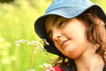 Portrait of a girl's head smelling meadow flowers on a meadow at sunset