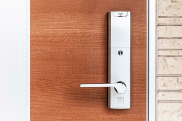 Entrance door handle close up. Lock and handle on the door. Reinforced door lock. Doorknob at a brown wood door