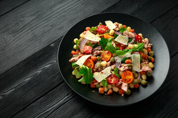 Mini potato gnocchi tricolour with tomato, spinach, Seasonal salad leaves and parmesan cheese on black plate