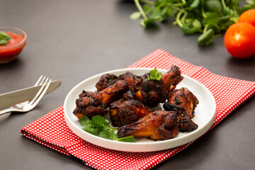 Roasted chicken legs, drumsticks on plate with fresh vegetables.