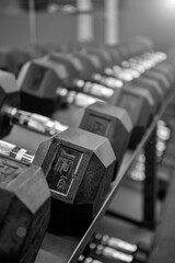Obraz premium Czarne hantle ustawione na siłowni. Bliska wiele metalowych hantli na stojaku w centrum fitness sportu. Koncepcja sprzętu do treningu siłowego.