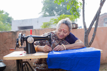 Indian women stitching cloths by machine at out side the home