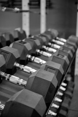 Black dumbbell set in the gym. Close up many metal dumbbells on rack in sport fitness center. Weight Training Equipment concept.