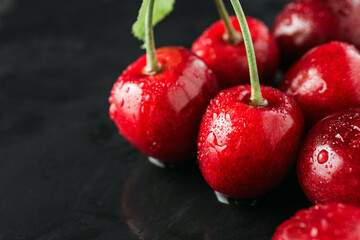 Fresh red cherries with water drops on dark background, close-up view