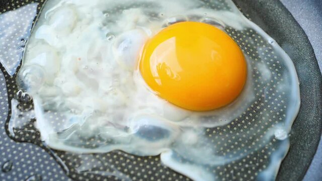 Close up slow motion video for the egg frying in the hot iron panto make fried egg for the breakfast 