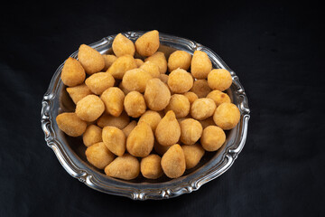 fried party snacks arranged on a stainless steel plate with black background. top view