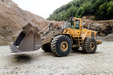 empty wheel loader machine loading gravel. Industrial machinery working with rock breaker and crusher, dumper trucks