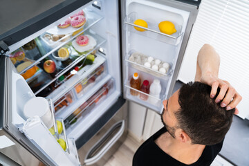 Hungry Confused Man Looking In Open Fridge