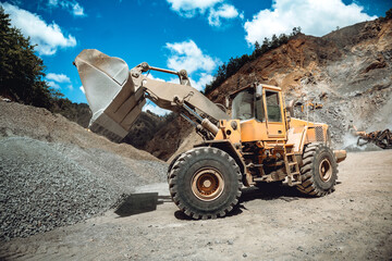 Industrial wheel loader working on construction site. Heavy duty machinery loading gravel and transporting materials