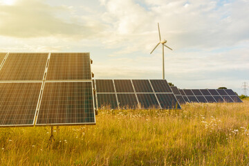 Solar panels and wind turbine at sunset, photovoltanic, alternative source of energy.