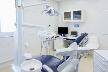 A modern interior of a dental office with white and blue furniture, dental chair, computer. Dentist’s office. Dental laboratory.
