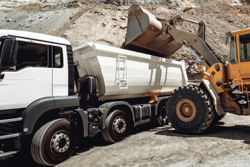 Industry details - industrial machinery working. Wheel loader loading gravel into dumper trucks. Transportation details © aboutmomentsimages