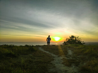 running guy on a hill with a beautiful view of the sunset