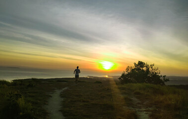 running guy on a hill with a beautiful view of the sunset
