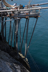 Typical traditional fishing trabucco on wooden poles at the beach with rocks near Vieste in Italy. 