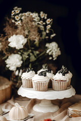 Candy bar. White wedding cake decorated by flowers standing of festive table with deserts, strawberry tartlet and cupcakes. Wedding. Reception Tartlets
