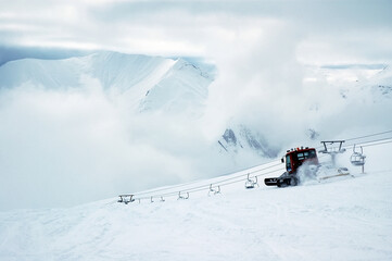 Cloudy winter mountainous landscape. View at the greater Caucasus mountain range, snowcat and ski lift. Gudauri ski resort. Georgia.
