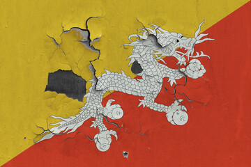 Bhutan flag close up old, damaged and dirty on wall peeling off paint to see inside surface. Vintage National Concept.