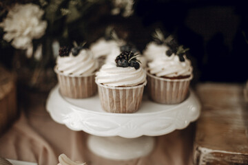 Candy bar. White wedding cake decorated by flowers standing of festive table with deserts, strawberry tartlet and cupcakes. Wedding. Reception Tartlets