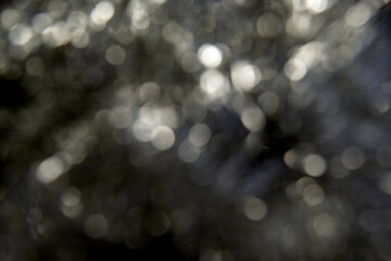 Abstract defocused black background with delicate white glitter bokeh.