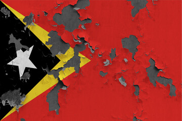 East Timor flag close up painted, damaged and dirty on wall peeling off paint to see concrete surface. Vintage National Concept.