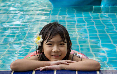 Asian cute child girl Swimming in the pool smiling happy