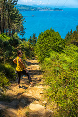 A young woman in a yellow shirt on the trail in the town of Orio, Guipuzcoa, Basque Country. Excursion from San Sebastián to the town of Orio through Mount Igeldo walking 3 friends.