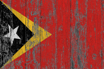 East Timor flag on grunge scratched wooden surface. National vintage background. Old wooden table scratched flag surface.