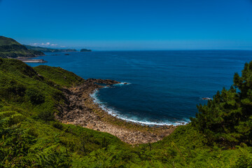 Hidden cove on the Orio coast and in the distance Getaria, Guipuzcoa, Basque country. Excursion from San Sebastián to the town of Orio through Mount Igeldo walking 3 friends.