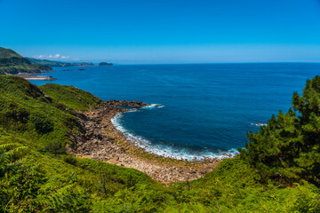 Fototapeta premium Detail of the viewpoint of the Orio coast seen in the distance Getaria, guipuzcoa, basque country. Excursion from San Sebastián to the town of Orio through Mount Igeldo walking 3 friends.